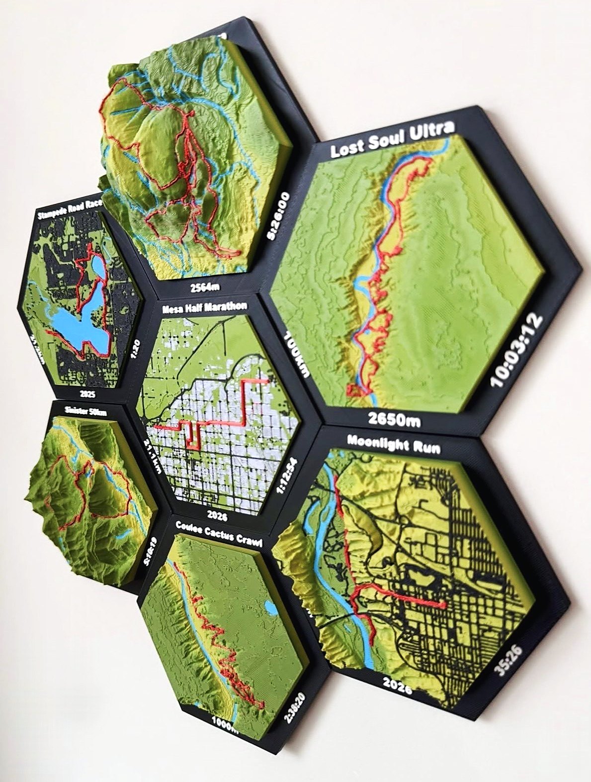 Seven hex tiles mounted together on a wall, including Lost Soul Ultra 100 km in 10:03:12, Mesa Half Marathon in 1:12:54, Moonlight Run, Coulee Cactus Crawl and Stampede Road Race.
